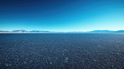 Vast salt flat landscape under a clear blue sky with distant mountains on the horizon