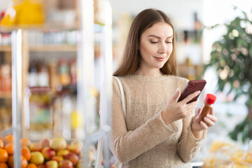 Female shopper scanning QR code on bottle ground pepper label in grocery department of supermarket