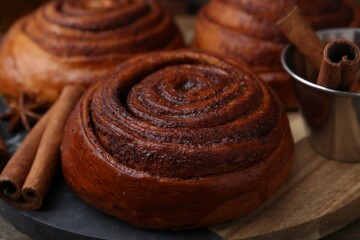 Fototapeta premium Delicious cinnamon roll buns and spices on wooden table, closeup