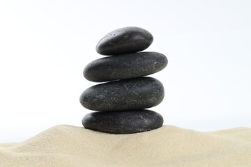 Stack of rocks on sand against white background. Harmony and life balance