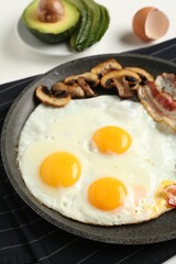 Tasty fried eggs with bacon and mushrooms served on table, closeup