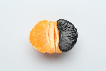 Stop racism. Half of tangerine with black piece on light background, top view
