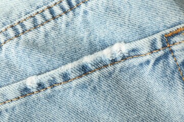 Ripped light blue jeans with pocket as background, top view