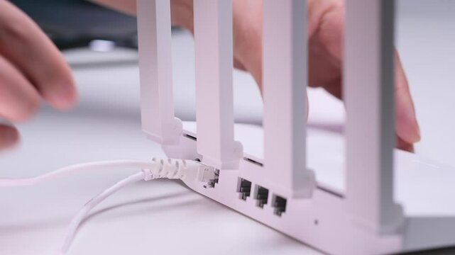Technician plugging ethernet cable into wireless router in office setting