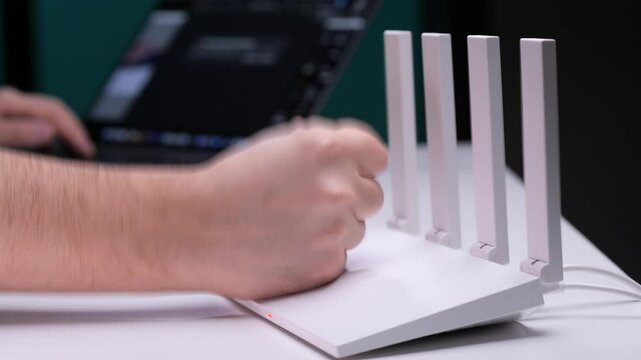 Frustrated programmer hitting wireless router while working on laptop