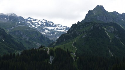 Majestic Alpine Mountain Range with Winding Trails and Snow-capped Peaks