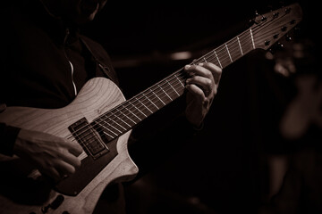 Fototapeta premium Close-up of a guitarist playing a light-colored electric hybrid guitar in jazz set.