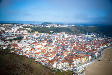 Fototapeta premium Aerial view of the town of Nazaré from atop cliffs, with red roofs.