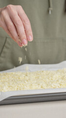 Grated cheese falls out of the cook's hand on pizza. Homemade pizza. Grated cheese for pizza.