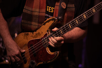 Obraz premium Close-up of a musician's hands playing a bass guitar during a live performance.
