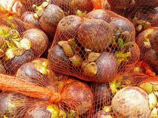 Close Up View Of Many Mangosteens In Orange Mesh Bags 