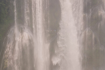 Close up on the water falling and people walking under the Huangguoshu Waterfall in Guizhou, China