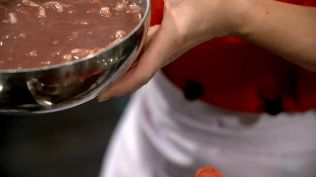 Pouring red bean porridge into a bowl with noodles