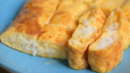 roll omelette stuffed with chesse and rice on blue plate, delicious food in the morning