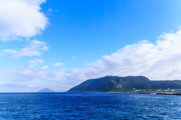 Fototapeta premium 振り返ると新島の2つの山と利島、鵜渡根島が見える。 新島港に接岸する東海汽船さるびあ丸。東京都伊豆諸島新島 - 2024 