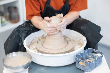 Close-up of a potter's hands working on a pottery wheel. 