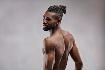Muscular black man showing his back and looking at the camera