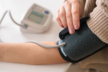 Woman at home trying to fight migraine and headache and measures blood pressure with tonometer