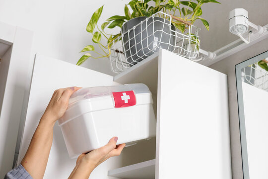 Female hands putting first aid kit with vitamins, drugs, antibiotics and cure at bathroom cupboard.