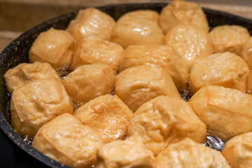 A chef is frying tofu in a pan in the kitchen