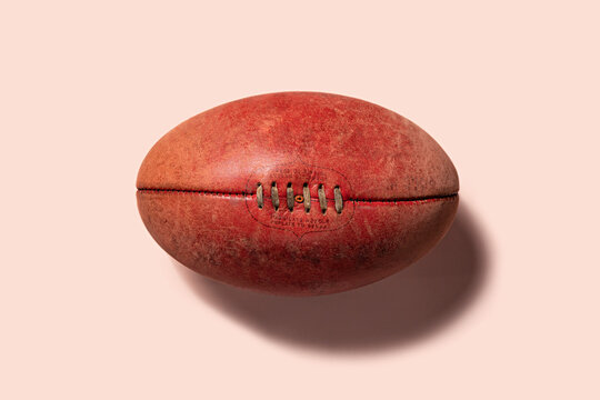 Australian Rules Football, AFL red leather football on a pink background