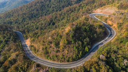 Aerial top view road in forest with car motion blur. Winding road through the forest. Car drive on the road between green forest. Ecosystem ecology