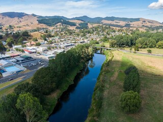 Naklejka premium High-angle view of Paeroa town nestled beside a river, with a bridge spanning the water. Tranquil rural scene. Ohinemuri River, Paeroa, Waikato, New Zealand