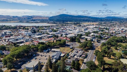 High-angle view of Rotorua showcasing residential and commercial buildings, a park, and a body of water. Sunny day, with clear skies and visible mountains.  Bay Of Plenty, New Zealand