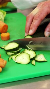Chef chopping vegetables on green board