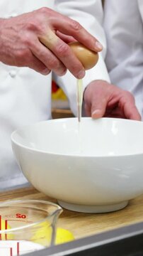 Chef cracking an egg into a bowl
