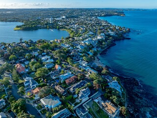 Coastal suburbia, New Zealand. Houses and streets, nestled beside the ocean. Aerial view. TAKAPUNA, AUCKLAND, NZ