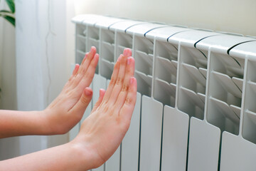 A child warms her hands near the radiator at home
