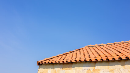 The roof tiles of the building have a background of blue skies of bright sky, Clay tile roof, Banner with orange clay tile roof close up on blue sky background with space for text, copy space.