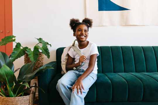 Happy afro girl getting ready for school at home