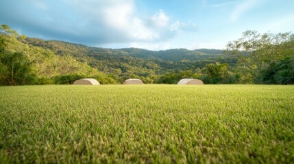 Three Beige Tents on Lush Green Field with Mountain Background