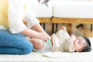 赤ちゃんの紙オムツを交換する母親
