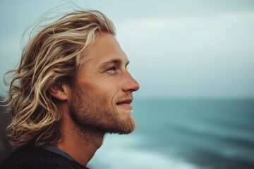 man with a soft smile wearing a wetsuit with ocean in the background