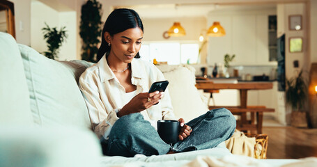 Woman, mobile and coffee on sofa with social media, reading blog and app subscription in home. Girl, warm beverage and phone in living room for relax, streaming video and green tea benefits research