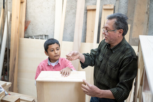Older man teaching carpentry to Latino boy