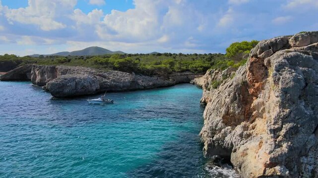 Explore Cala Varques in Porto Cristo, Majorca, where crystal-clear waters meet rugged cliffs. Enjoy the natural beauty of this coastal paradise surrounded by lush greenery.
