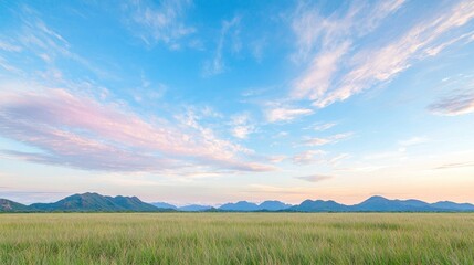 Serene sunset over grassy field and distant mountains