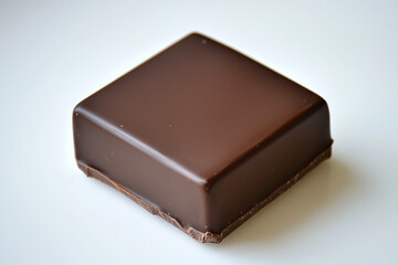 Obraz premium A Single Square of Dark Chocolate Resting on a Minimalist White Backdrop.