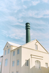 Reykjavik chimney rising above building under blue sky with clouds