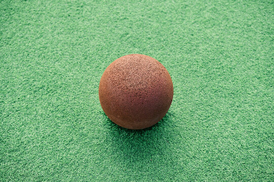 Brown ball lying on green artificial turf