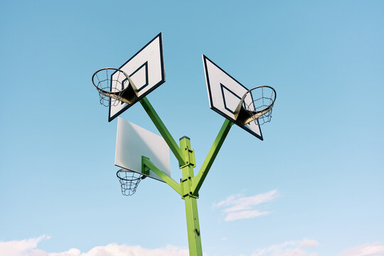 Three basketball hoops pointing in different directions under blue sky