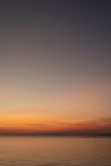 Soft gradient sunset over calm ocean waters with a vast sky