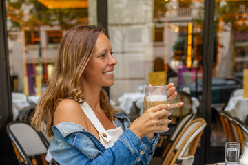 Smiling woman enjoying a coffee outdoors at a Paris café