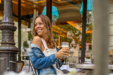 Smiling woman enjoying a latte coffee at a Parisian café.
