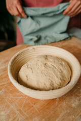 A sourdough bread dough in a bread basket getting ready for proofing