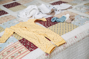 Set of baby clothes on bed with plaid